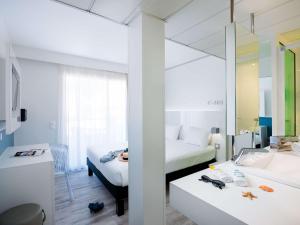 a hotel room with two beds and a mirror at Ibis Styles Menton Centre in Menton