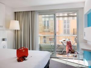 a hotel room with a bed with a red bag on it at Ibis Styles Menton Centre in Menton