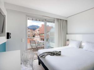 a hotel room with a bed and a balcony at Ibis Styles Menton Centre in Menton