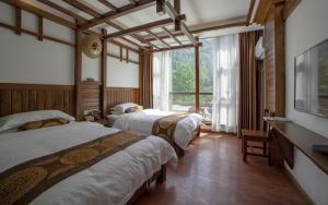 um quarto com 3 camas e uma grande janela em Zhangjiajie Memory Inn em Zhangjiajie