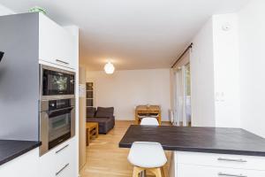une cuisine avec des placards blancs et un salon dans l'établissement Large apartment near Bois de Vincennes, à Charenton-le-Pont
