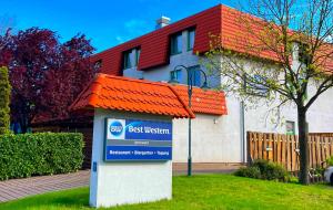 a sign in front of a house with a red roof at Best Western Spreewald in Lübbenau +47 photos