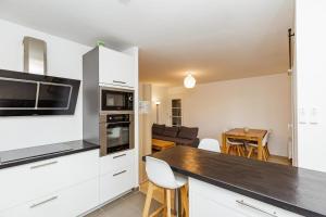 une cuisine avec des placards blancs et une table avec des chaises dans l'établissement Large apartment near Bois de Vincennes, à Charenton-le-Pont
