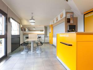 ein Büro mit einer gelben Theke, einem Tisch und Stühlen in der Unterkunft hotelF1 Sens Nord in Sens