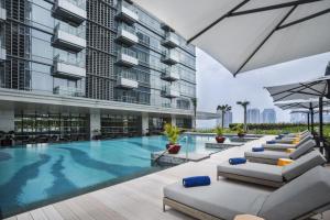 a swimming pool in a building with lounge chairs at Ascott Kuningan Jakarta in Jakarta