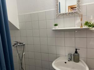 uma casa de banho em azulejos brancos com um lavatório e um espelho. em Pensiunea Bianca em Bran