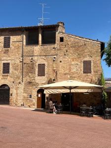 una persona sentada bajo un paraguas delante de un edificio en A La Casa Dei Potenti, en San Gimignano