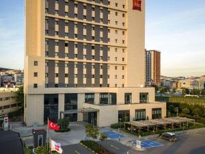 a large building with a parking lot in front of it at Ibis Istanbul Tuzla Hotel in Tuzla