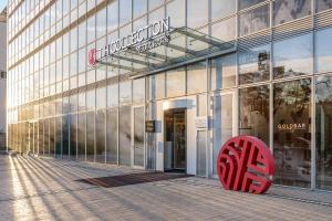 a large glass building with a red object in front of it at NH Collection Köln Mediapark in Cologne