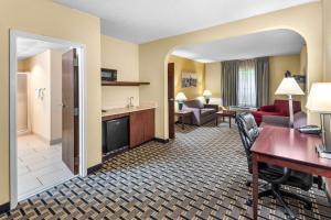 a hotel room with a desk and a living room at Clarion Inn & Suites Northwest in Indianapolis