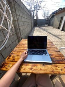 Da! Hostel في بيشكيك: شخص يجلس على طاولة خشبية مع جهاز كمبيوتر محمول