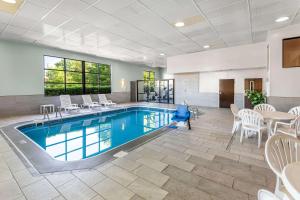 una piscina en una habitación de hotel con sillas y mesa en Clarion Inn & Suites Northwest, en Indianápolis