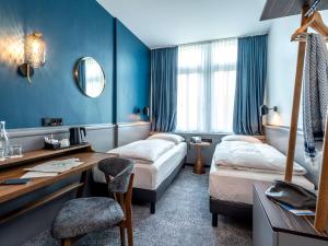 a hotel room with two beds and a desk at Mercure Hotel Luebeck City Center in Lübeck