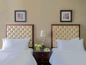 麥加的住宿－麥加皇家鐘樓費爾蒙酒店，两张带白色床单的床和酒店客房内的床头板