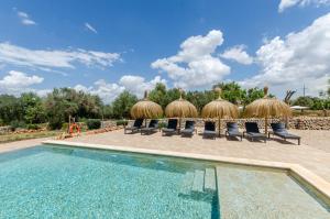 ein Resort mit einem Pool mit Stühlen und strohgedeckten Sonnenschirmen in der Unterkunft Agroturismo Cal Tio 3 YourHouse in Costitx