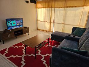 a living room with a couch and a table and a tv at Bintara Guesthouse Sri Sayang Batu Ferringhi in Batu Ferringhi