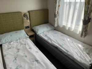 two twin beds in a room with a window at Robyn’s Nest in Lybster