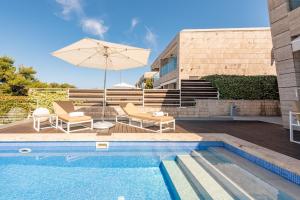 a swimming pool with two chairs and an umbrella at Villa Lantana ZadarVillas in Petrcane