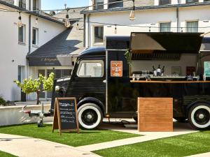 um velho camião de comida preta estacionado em frente a um edifício em ibis Styles La Roche-sur-Yon em Mouilleron-le-Captif