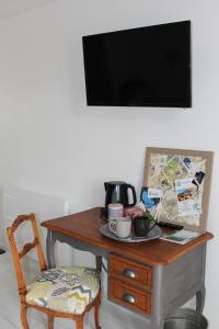 mesa con silla y TV en la pared en Bocage et Coquillage, en Gouville-sur-Mer