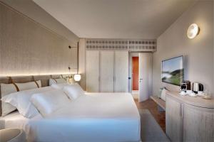 1 dormitorio con 1 cama blanca grande y escritorio en Veridia Resort Sardinia, a member of Radisson Individuals en Chia