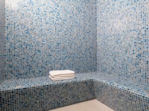 a blue tiled bathroom with a towel on a bench at Novotel Riyadh Sahafa in Riyadh