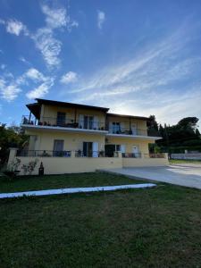 a large white building with a grass yard in front of it at La vita e Bella Apartments by Corfuescapes in Kontokali
