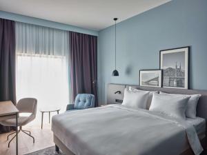Radisson Hotel Graz في غراتس: غرفة نوم بسرير كبير وجدار ازرق