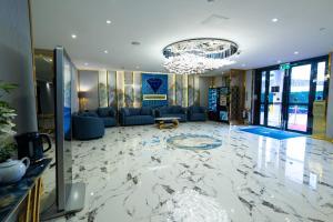 una hall con pavimento in marmo e lampadario pendente. di Grand Sapphire Hotel & Banqueting a Croydon