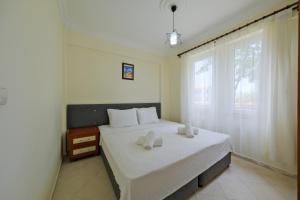 a bedroom with a bed with white sheets and a window at Larimar Suite Hotel in Oludeniz