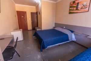um quarto com uma cama, uma secretária e uma mesa em Alfa Hotel Vespasiano em Vespasiano
