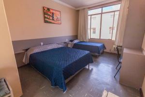 Habitación con 2 camas y ventana en Alfa Hotel Vespasiano, en Vespasiano