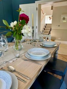 una mesa de madera con platos y un jarrón de flores en Luxury farmhouse in secluded Cotswold valley en Uley