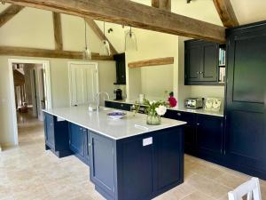 Luxury farmhouse in secluded Cotswold valley في Uley: مطبخ مع دواليب زرقاء وقمة بيضاء