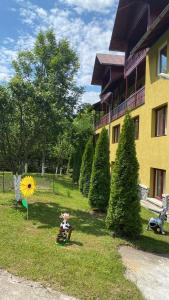 a yellow building with a yard with trees and a house at Vila Drumetului in Comarnic
