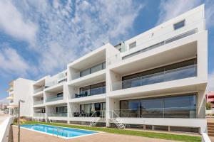 a white apartment building with a swimming pool at Dália modern apartment Five minutes to beach in Luz