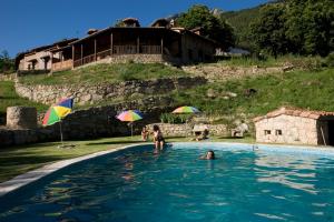 un grupo de personas en una piscina con sombrillas en Hotel Rural Abejaruco, en Cuevas del Valle
