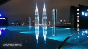 a swimming pool with a fountain in front of theida towers at night at MOONWAY SUITES At EATON KLCC in Kuala Lumpur