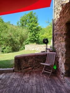 a chair sitting on a wooden porch with a camera at chambre ciel et terre et chambre terrasse in Saint-Laurent-de-Cerdans