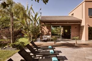 a patio with two lounge chairs and a house at Villa Fuerte Chania - Including Two 7-seater Vans, Airport Shuttle, Breakfast in Alikianós