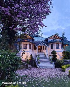 une maison avec un arbre planté de fleurs violettes dans l'établissement Walauwa on the hill, à Hatton