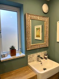 a bathroom with a sink and a mirror at Cotswold Retreat in Cheltenham +13 photos