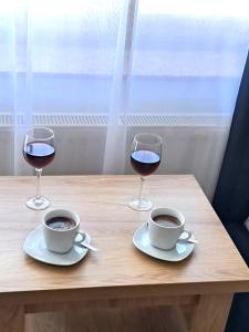 クリニツァ・モルスカにあるWilla Rubin z WIDOKIEM NA ZALEWの木製テーブルに置かれたワイン2杯とコーヒー2杯