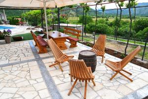 un patio con sillas, una mesa y una sombrilla en Gazdinstvo Vukanović - Kuća za odmor, en Trebinje