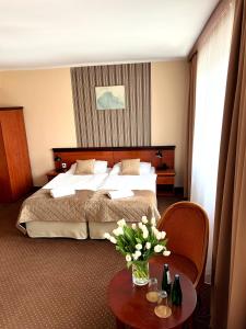 pokój hotelowy z łóżkiem i stołem z kwiatami w obiekcie Załęże w mieście Katowice