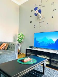 ein Wohnzimmer mit einem Sofa und einem TV mit einer Uhr in der Unterkunft Horizon heights 2 in Kira