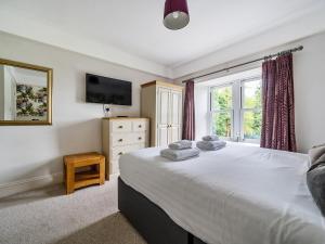 um quarto com uma cama e uma televisão na parede em The Oaks em Windermere