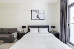 a bedroom with a large white bed and a couch at Studio Huge Balcony Loreto 1 Damac Hills in Dubai Marina