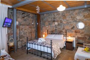 a bedroom with a bed and a stone wall at Fikardou Chalets in Phikardhou