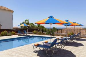 a group of chairs and umbrellas next to a swimming pool at Villa Antonia by Villa Plus in Peyia